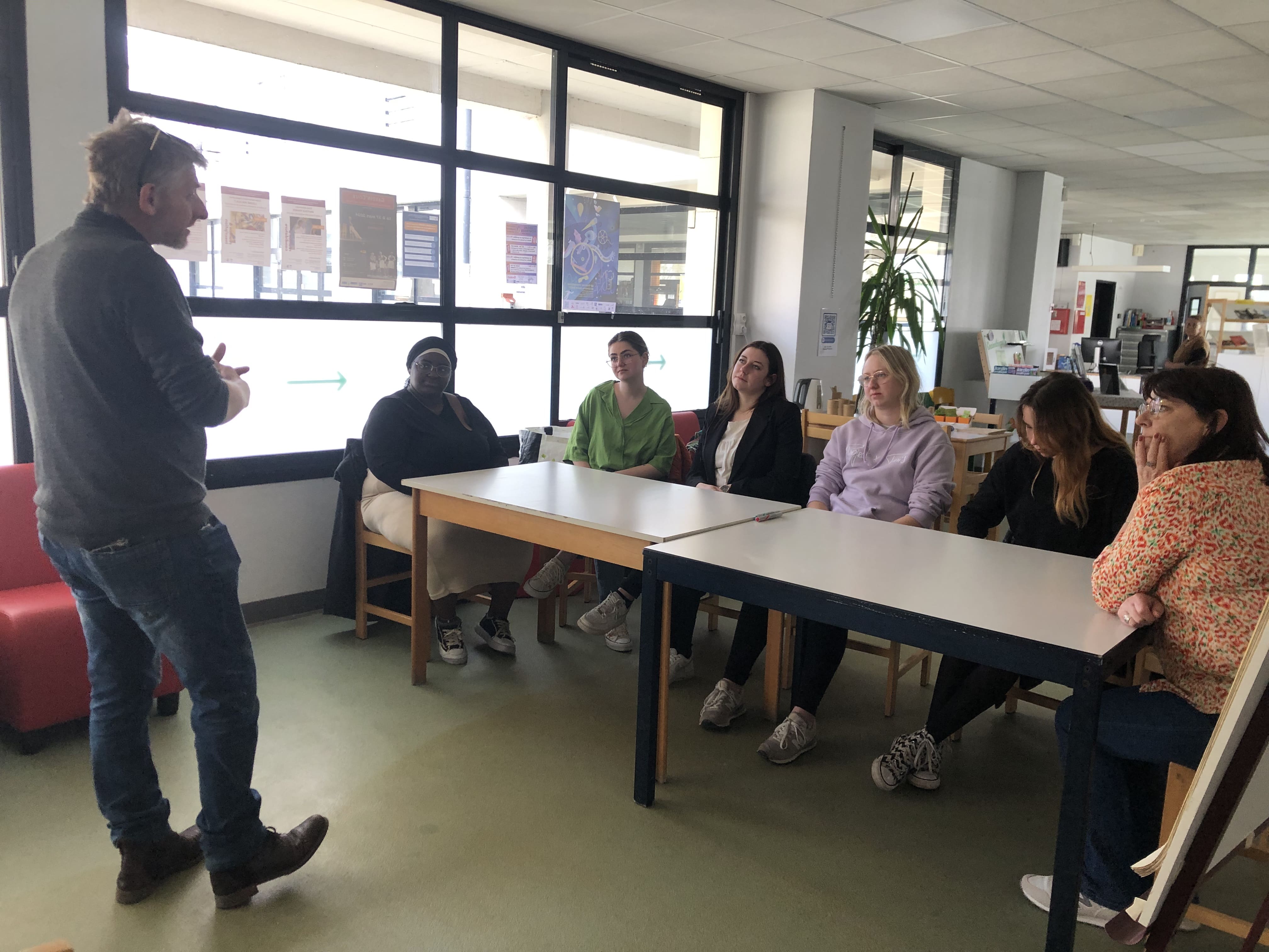 un homme devant des femmes assises